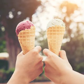 two hands holding icecreams ot each other